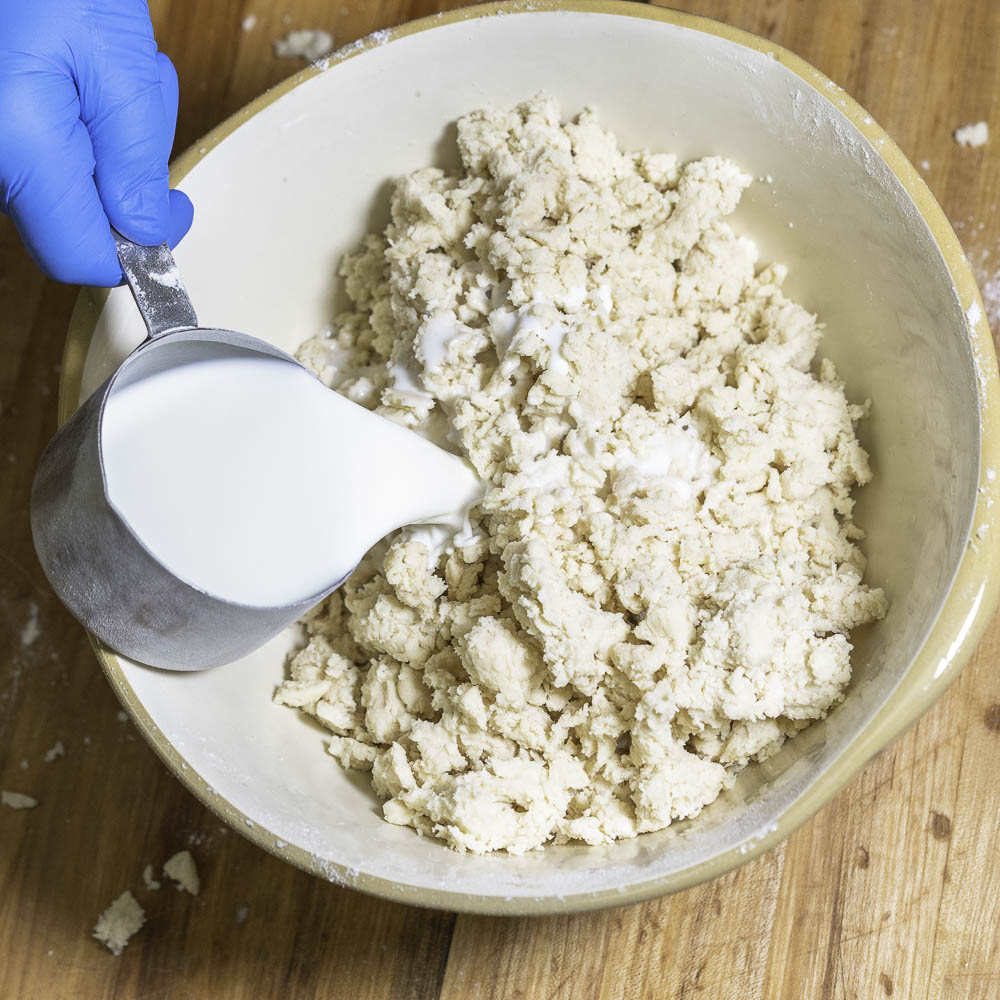 photo of a strawberry rhubarb pie hand pouring milk into mixture