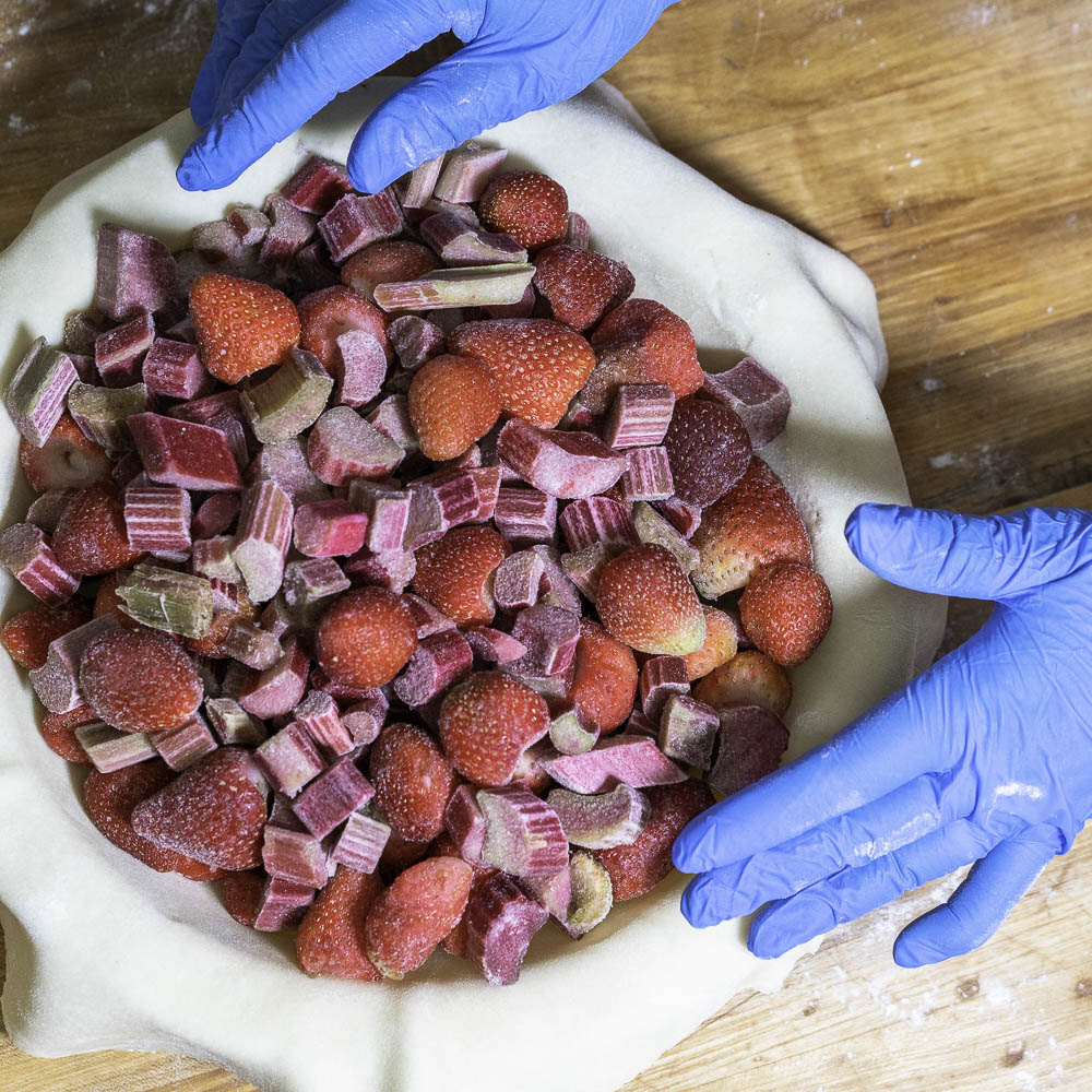 photo of a strawberry rhubarb pie adding frozen strawberries and rhubarb