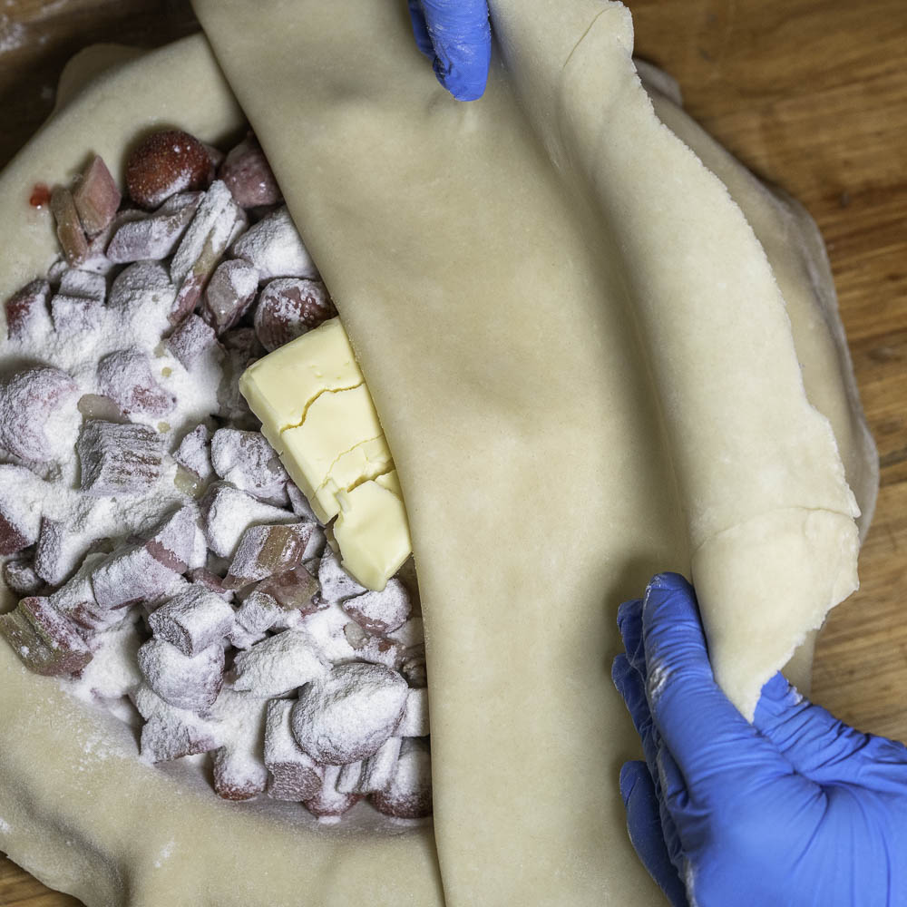 photo of a strawberry rhubarb pie top crust being added