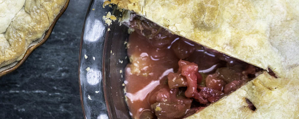 photo of a strawberry rhubarb pie with a piece missing