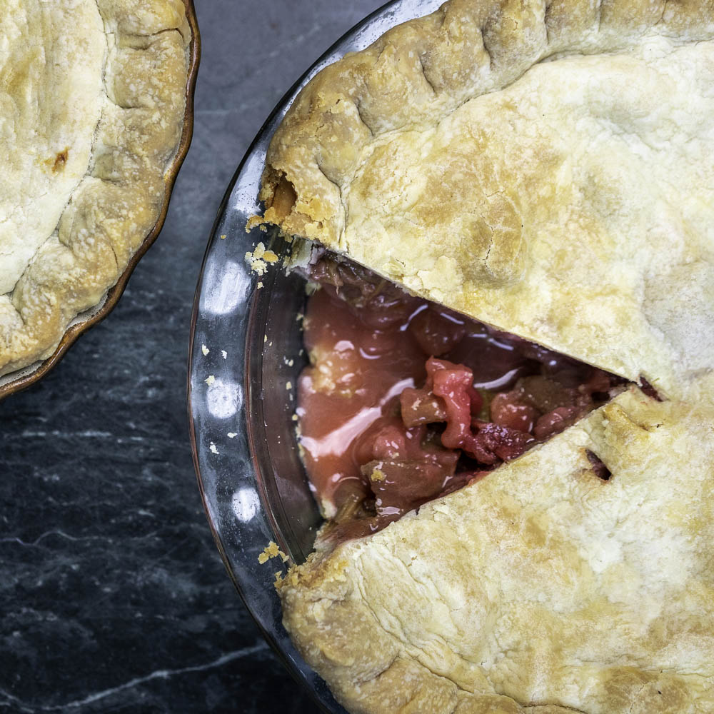 photo of a strawberry rhubarb pie with a piece missing